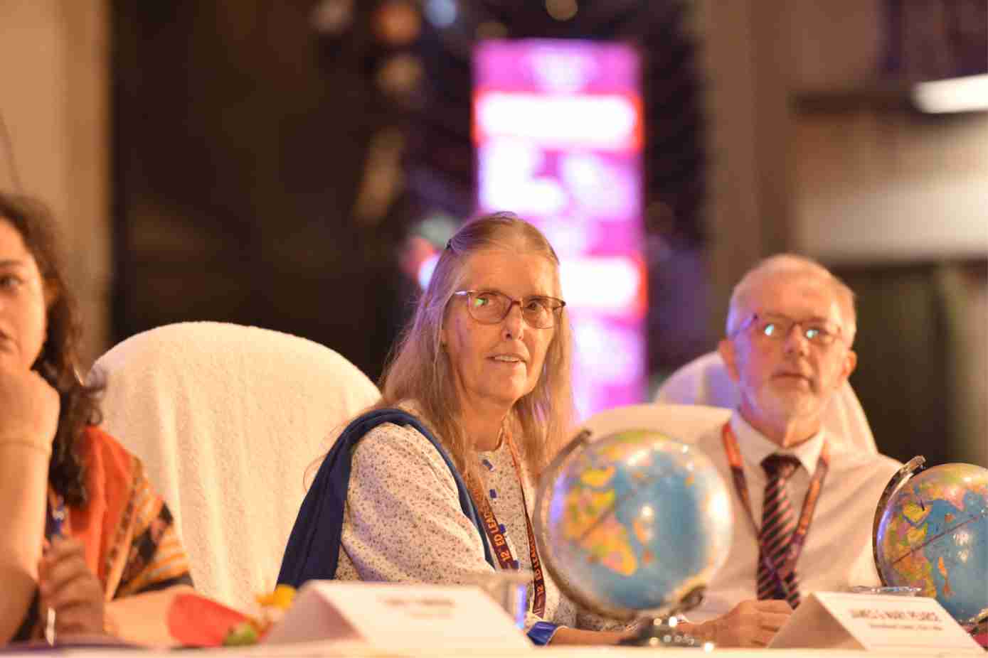 International delegates seated at a conference table with desktop globes during a panel session